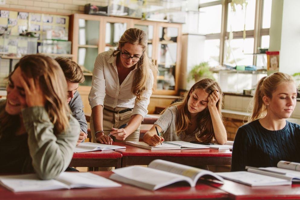 A doctoral research assistant is in a seminar room in the midst of her students. She enjoys teaching, but is also aware that she still needs to raise her academic profile through other achievements.