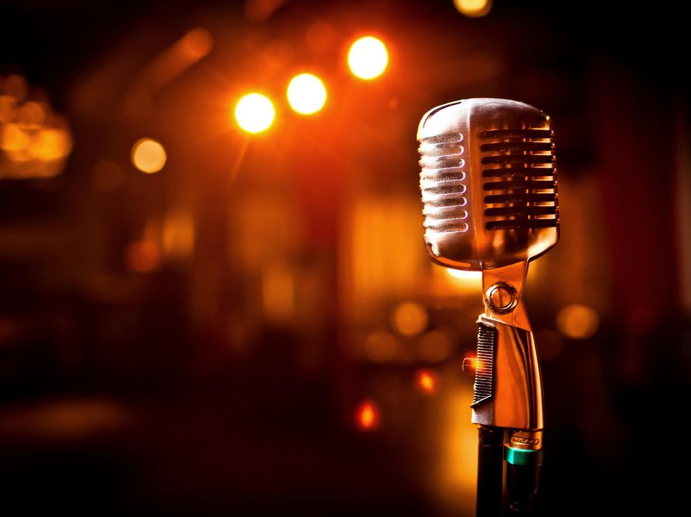 Das Bild zeigt ein Mikrofon auf einer Bühne.