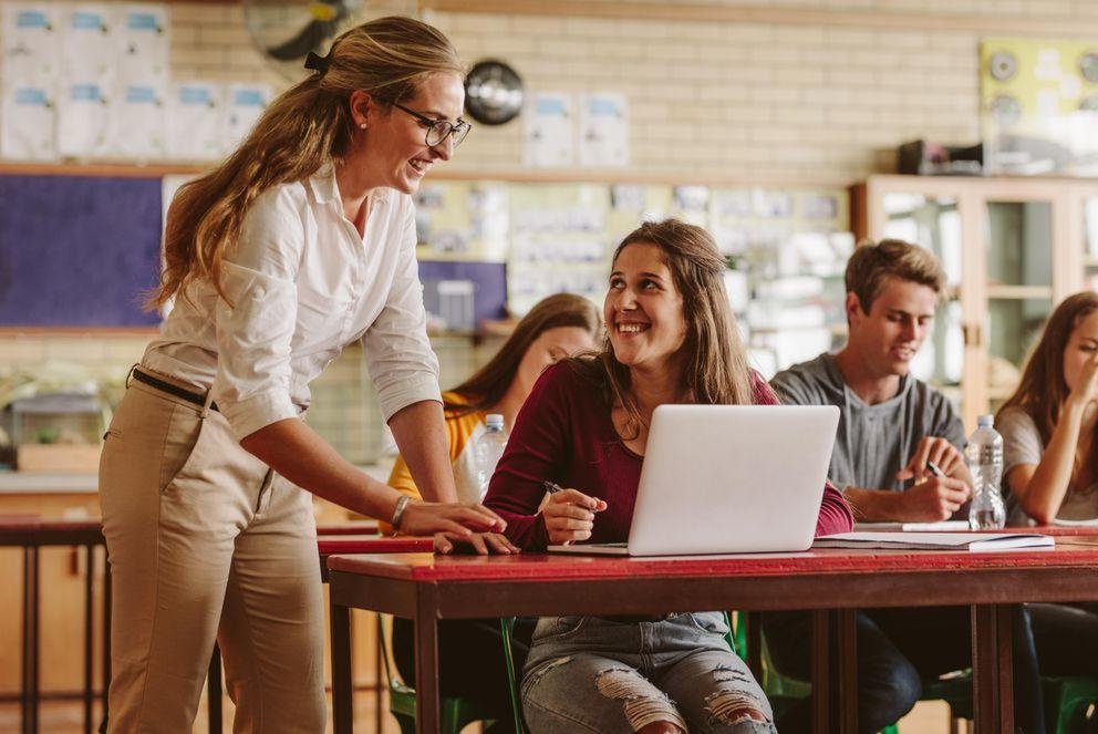 Woman high school professor helping student in class Eine Dozentin gibt einer Studentin in einem Seminarraum Hilfestellung zur Lösung der Aufgabe.