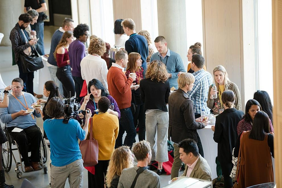 The picture shows a conference with a diverse crowd of people.